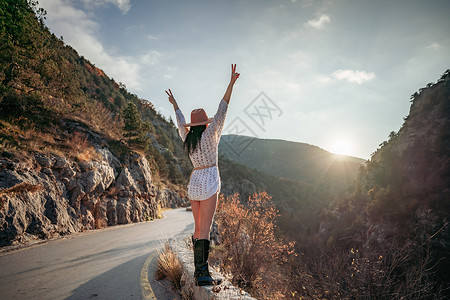 穿着棕帽子和白色毛衣的女旅行者 看着惊人的山峰和森林 漫游概念 大气史诗时刻女性流浪者女孩自由旅游游客山脉假期远足潮人背景图片