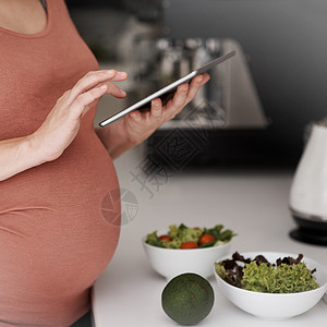 孕妇用药检查她的饮食计划 一个孕妇在厨房吃沙拉时 使用平板糖用药背景