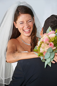 做人开心最重要在他们的重要日子里玩得最开心 一位欣喜若狂的年轻新娘拿着花束拥抱她的丈夫背景