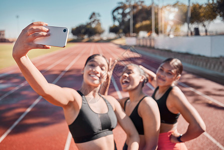 女跑步者团体在跑道上进行健身 交友和自拍 以进行训练 锻炼和有氧运动 运动 电话和女队在体育场锻炼后微笑 放松并摆姿势拍照背景图片
