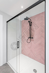 现代洗手间有粉色和白色瓷砖 雨头 手握淋浴和玻璃门高清图片