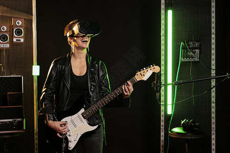 虚拟摇杆素材带虚拟现实耳机的吉他手一边用电吉他演奏重金属歌曲一边享受摇滚音乐会模拟背景