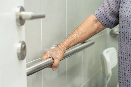 栏杆扶手亚洲老年或老年老妇人病人在护理医院病房使用厕所浴室手柄安全 健康强大的医疗理念座位淋浴洗手间退休金属房间洗澡酒店合金潮红背景