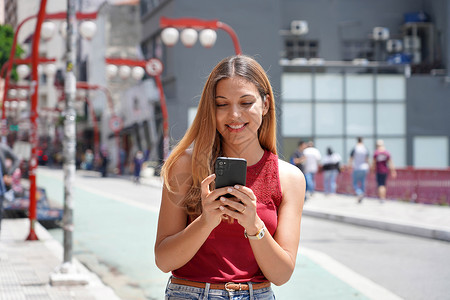 解放时尚风潮在巴西圣保罗散步时 快乐美丽的微笑少女用手机聊天电话学生晴天音乐城市青年解放红灯美女街道背景