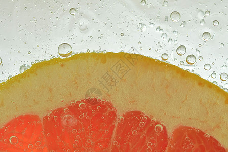 白色背景水中的红葡萄柚片 葡萄柚在带有气泡的液体中的特写镜头 片红色成熟葡萄柚在水中 水果在水中的宏观形象饮食热带柚子饮料飞溅果背景图片