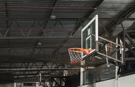 篮球框侧面在篮球法庭上 篮球纤维玻璃后板与橙色篮球圈金属环和白橙网的侧面视图背景