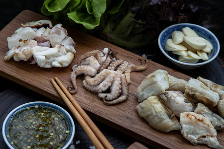 新鲜的烤鱿鱼 章鱼触手和乌贼蛋 在木质盘上触角营养美食黑色背景饮食木头乌贼摄影食物图片