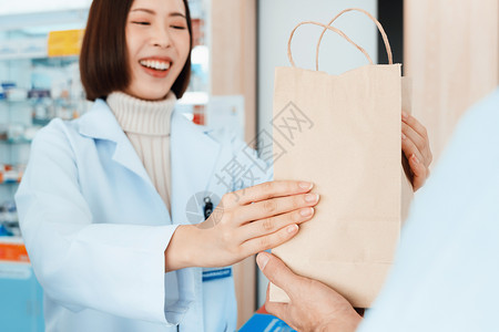 复旦大学附属中山医院附属药剂师将合格的药品交给药店的顾客微笑病人出纳员架子服务工作零售店铺女士外套背景