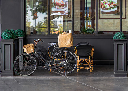 店面前台旧黑色自行车停在咖啡馆和餐馆前面 外出设计和前台装饰品上家具商业木头咖啡店店面车辆零售饮料大车展示背景