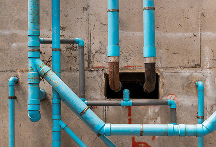 公寓大楼混凝土墙上的蓝色水塑料管 在建筑物中安装排水管 公寓的卫生系统 水管系统安装在混凝土天花板上控制插座塑料衣架路口下水道工背景图片