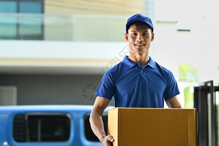 送货员携带纸板包裹 对着照相机微笑的身影画像 送货服务 邮递和运输概念背景图片