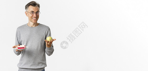 长着眼镜的英俊和健康的中年男子形象 建议吃苹果而不是蛋糕 站在白色背景上 笑声胡须商业成人广告诱惑头发男性工作室促销发型背景图片