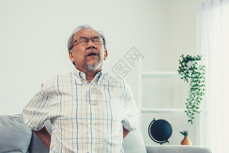 一个痛苦的老人因为背部疼痛而忍住后背护理女性房间工人医生家庭帮助志愿者医院保健背景