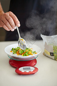 蔬菜是每餐一餐的必备品 被刻画成一个人把熟菜勺在厨房里背景图片