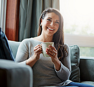 坐在客厅的沙发上 坐在客厅的沙发上 和她家里的女人一起喝咖啡 思考和放松 创意 茶和生活方式 一位迷人的年轻女性在休息室的沙发上背景图片