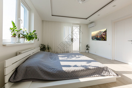 床上用灰色毯子和木头床铺在简单的卧室内室内 黑海报和窗下的椅子床头家具床单枕头绘画靠垫房间音调窗户公寓背景图片