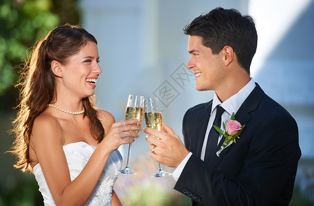 新婚来袭两个年轻的新婚夫妇用香槟互相敬酒 来庆祝我们和我们的下半辈子背景