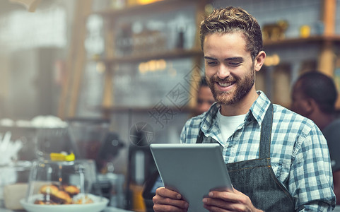 利用现代技术紧跟小型企业趋势 一个年轻人在他工作的商店里使用数字平板电脑背景