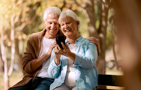 5g来了放松 快乐 并与公园里的老夫妇通电话 进行视频通话 社交媒体和交流 微笑 健康和互联网 男人和女人坐在大自然的长凳上退休 5g背景