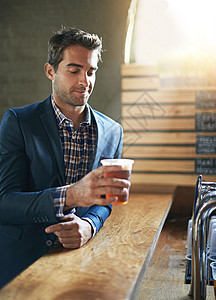 他一整天都在盼着这啤酒 一个男人在他当地的酒吧享用冰镇啤酒背景图片