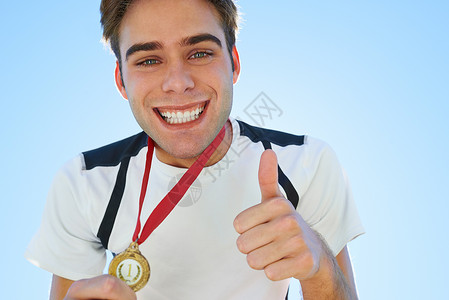 骄傲的体育时刻 微笑的奖牌得主带着笑容挥舞着拇指高清图片