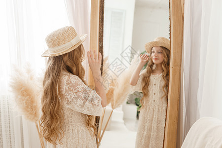 长发的美少女在镜子前戴上草帽 对金发女郎的自以为是的感觉身体验收达人帽子洞察力女士青少年风格稻草干草背景