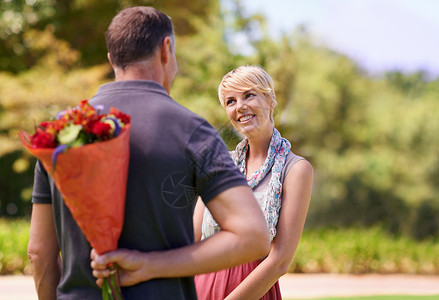 我有一个惊喜给你 一个成熟的男人背着他的女朋友 藏了一束鲜花来向你隐瞒他背景图片