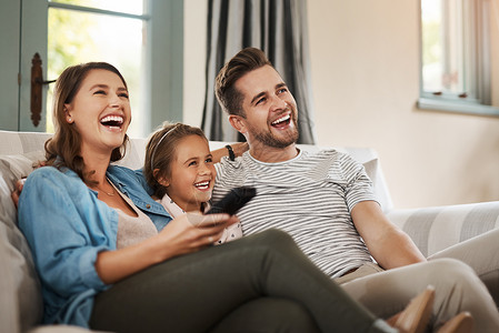 站住就是你完美的周末就是和你爱的人在一起 一个快乐的年轻家庭在沙发上放松 在家里一起看电视背景
