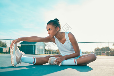 一位有吸引力的年轻女子独自坐在网球场上 在练习前伸展了长镜头 在开学前 她被拍了一整张照片背景