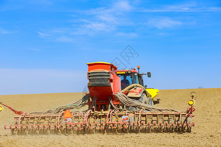 一台在田间撒种种子的拖拉机播种谷物 从一个春季田间工程综合体中进行背景