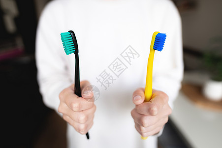女人的手握着两个牙刷 牙科方向 已婚夫妇的早间卫生主题 笑声药品蓝色刷子塑料牙医女孩白色医疗家庭生活手臂背景图片