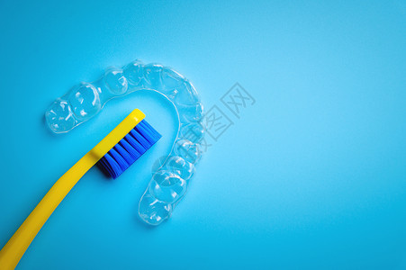 黄色牙刷一个黄色的明亮牙刷 上面有塑料新牙套 是蓝色背景 没有人口腔科卫生刷子对准器矫正固定器牙科牙医括号化妆品背景