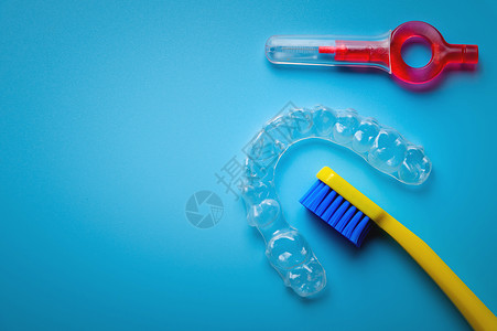 蓝色背景上带透明塑料对准器和牙间刷的牙刷 牙科诊所横幅刷子固定器括号口腔科矫正牙医化妆品卫生治疗保持器背景