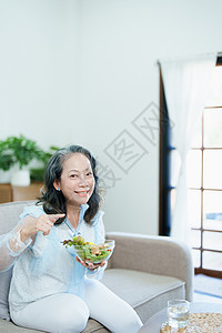 吃急眼了一位年长的亚洲妇女通过吃沙拉来照顾自己的健康午餐退休老年水果祖母成人女性烹饪食品微笑背景