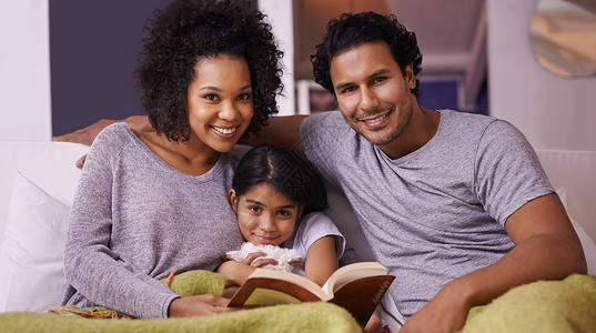 她们喜欢做父母 母亲和父亲对女儿说书;她们很享受作为父母的快乐背景图片