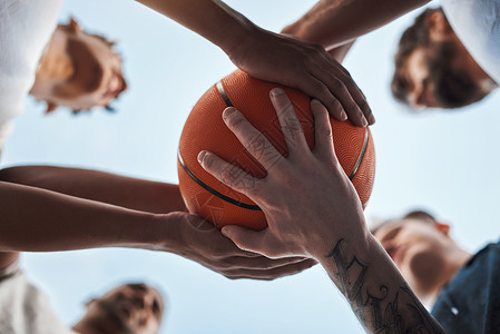 体育是教会团队合作的好方法 一组运动青年男子在体育法庭上围着篮球赛进行近距离拍摄背景图片
