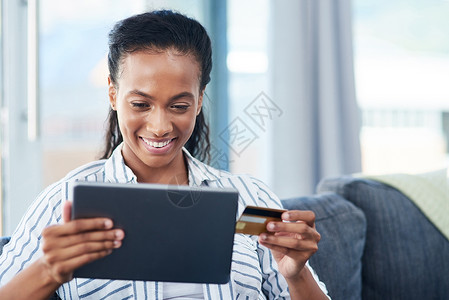 我要买下这个 一个年轻女人 在家里用信用卡和数字平板电脑做客背景图片