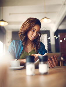 一个在咖啡馆里用数字平板电脑的迷人年轻女性 一位有吸引力的年轻女子背景图片