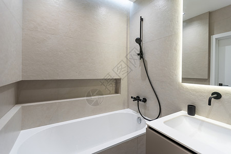现代风格的浴室 铺有灰色和白色瓷砖 有一面带夜光灯的大镜子 带木抽屉和水槽的桌面 带淋浴和玻璃隔断的浴缸 毛巾架和衣架装饰公寓木背景图片