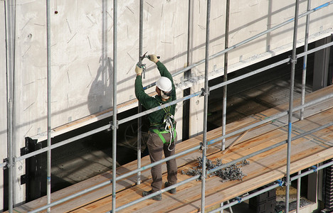 使用锤子的建筑工人劳动建筑项目安全头盔男人工作安全带工具腰带背景图片