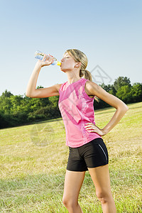 运动女人喝饮料慢跑饮食运动服蓝天公园饮料服装成年女性生活外表背景