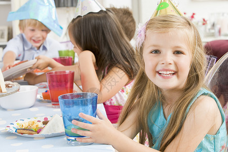 餐正试营业参加派对的年轻女孩坐在餐桌边吃着微笑的食物孩子生日果汁橙汁相机女性桌子孩子们水平背景