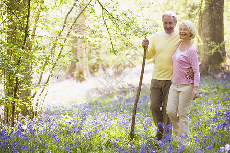夫妇在户外行走时微笑着手杖女士退休女性木头享受男性两个人男人季节公园森林高清图片素材