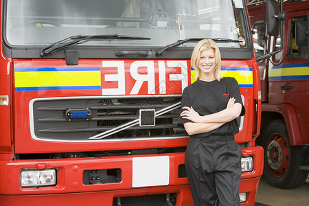 一名消防员站在消防机旁边的肖像情况消防车消防女性服务好榜样女士水平英雄消防队员背景图片