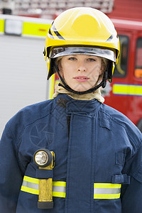 女消防员一名消防员站在消防车前的肖像英雄服务情况手电筒女性消防服好榜样消防火炬头盔背景