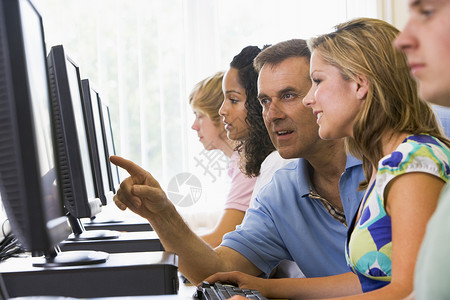 教师在计算机实验室协助大学生的师资学习技术课堂屏幕电脑中年水平五个人老师微笑背景图片
