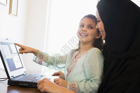 带笔记本电脑微笑高键选择性重点的在职母亲和女儿感情人种年龄小学外表孩子们亲热成年人孩子焦距背景图片