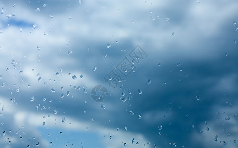 蓝色云雨滴在玻璃和天空上降下雨水背景