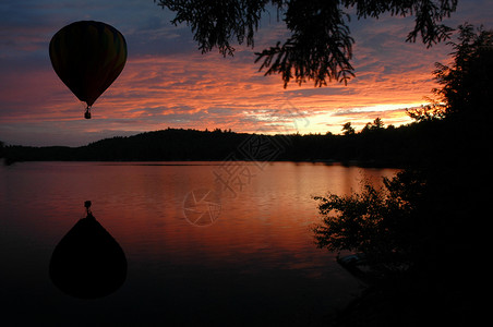 日落升起时在湖上空的热空气气球高清图片