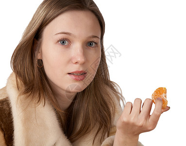 穿毛皮大衣的女孩拿着橘子高清图片